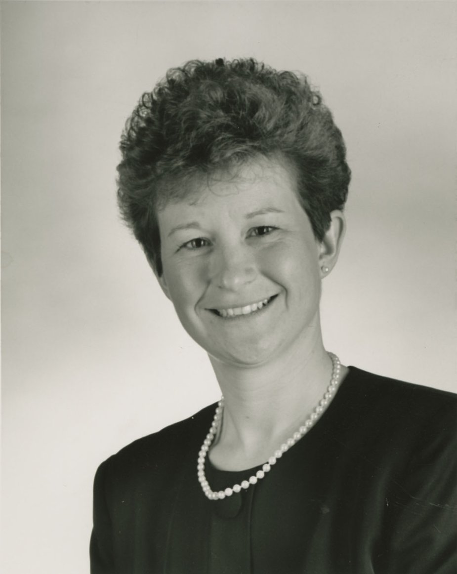 Image Description. Black and white photograph of a Caucasian woman with short brown hair, smiling.
