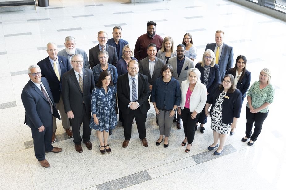 About 20 people gather in a marble-floored lobby. The photographer is shooting the photo from above and everyone is looking up.