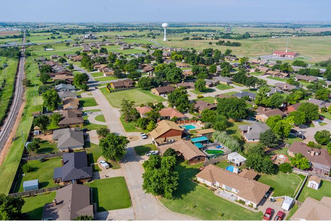 Nestled against old Route 66, Clinton, Oklahoma, has mainly one-story homes, mature trees, and plenty of grass. It's a sunny day, and the photo was taken from the air. You can see for miles.