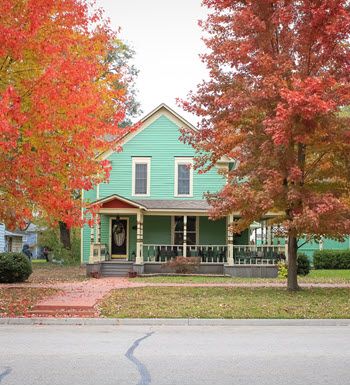 It is fall in Ottawa, Kansas. A sweet little turquoise blue bungalow peeks out between two large trees, their leaves a vibrant red.